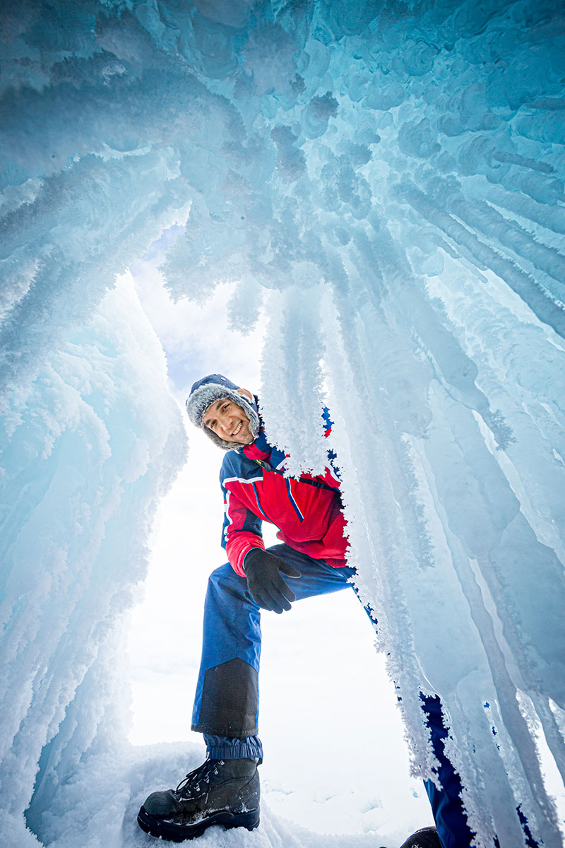 Turist egy jégbarlang bejárátanál a Bajkál-tó jegén Szibériában Oroszországban